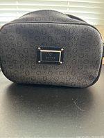 Exterior of a Guess pleather purse showing logo pattern and gold metal plate with Guess name and clasp detail