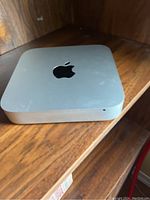 Apple Mac Mini computer top view showing silver aluminum finish and black Apple logo.