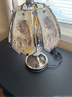 Full view of the touch lamp showing leopard design panels on the multi-sided lampshade and shiny metal base.