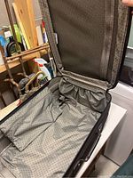 Open suitcase interior showing multiple compartments, elastic pocket, and zippered lid compartment with dotted lining interior.