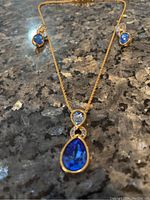 Necklace and earrings displayed on a dark granite surface to show design and colors of crystals and metal style.