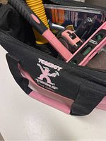 Close-up view of TOMBOY labeled black and pink tool bag filled with tools