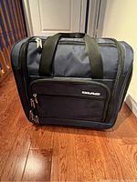 Front view of blue Caio travel on bag with multiple zippered compartments and dual handles.