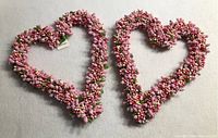Two heart-shaped wreaths placed side by side showcasing their shape and floral detailing.