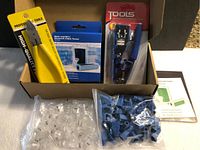 Full kit contents showing crimp tool, cable tester in packaging, pliers with yellow handle, and bags of connectors and boots in box.