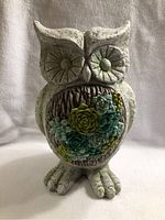 Front view of owl statue showing floral details on chest and textured finish