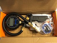 Digital tire pressure gauge with hose, inflator gun, and accessories inside orange AstroAI box.