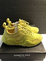 Side profile of lemon yellow Kenneth Cole Maddox women's sneaker on box