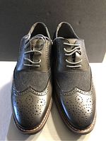 Front view showing detailed leather and fabric upper with perforated brogue pattern and laces.