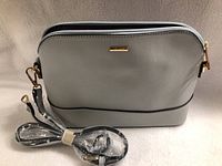 Front view of light gray Lovevook purse showing zipper and gold-tone hardware with separate strap wrapped and secured.