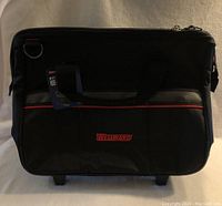 Front view of the black Westward rolling tool bag with red logo, showing the fabric exterior and front pockets.