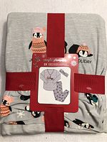 Folded pajama set packaged with label, showing penguin prints and winter theme design.
