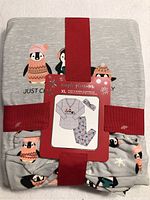 Folded pajama set in packaging with a visible tag showing penguin graphics and text 'Just Chilling for the Holidays'