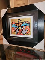 Framed fine art print shown side angle with protective corner covers on frame, displaying black frame and colorful Thunderbird design artwork.