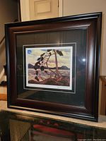 Framed fine art print displayed on surface, showing wood grain style frame with dark reddish-brown to black finish.