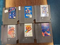 Top down photo showing all 6 NES cartridges laid out in two rows on a wood surface.