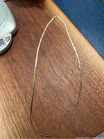 Full length view of the silver snake chain necklace laid out flat on a wooden surface.