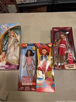 Four boxed dolls displayed together including Glinda, two High School Musical 3 dolls, and Jessie from Toy Story 2.