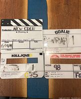 Four clapper boards laid flat on a wooden surface showing production details and dates from 2016 to 2018.