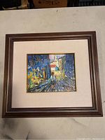 Full view of framed oil painting on canvas showing a street scene with impressionistic style and vibrant colors.