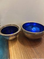 Both sterling silver bowls with blue liners side by side showing exterior tarnish
