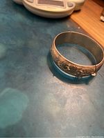 Sterling silver bangle showing chased floral designs and clasp