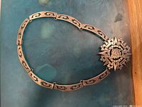 Full view of silver necklace with large decorative pendant in shape of a circle with lion motif, showing its shape and design.