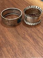 Photo of both sterling silver napkin rings showing enamel decoration and embossed patterns