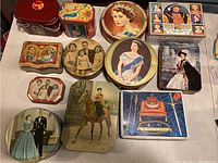 Overview of 13 vintage royal tins showing various royal portraits and coats of arms.