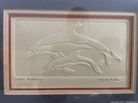 Framed embossed print of three dolphins signed and numbered 174/235 by Nora K. Fischer.