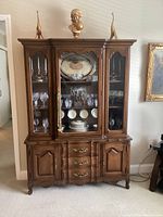 Full front view of the wood china cabinet assembled and staged with contents (not included).