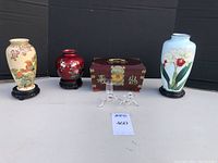 Full lot of three vases, red trinket box, and glass bud vase/candlestick holder on a display surface with dark backdrop for clarity.