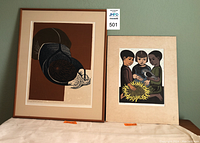 Two framed prints side by side on table, woodcut on left and poster on right