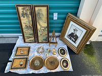 Full lot showing all items including the Asian panels, framed art, cherubs, plates, gold cat, decorative frame, and easel stand.