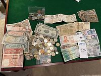 Photo showing a spread of paper currency and coins on green felt, with clear view of Canadian bills and various coins in a small plastic container and loose on the table.
