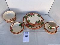 Front view of all ceramic pieces including plates, bowls, saucers, and one teacup arranged in groups with Franciscan Apple pattern