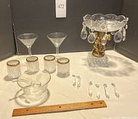 Full set showing glass bowl with ladle, four votive candle holders with brass trim, two martini glasses, six chandelier crystals, and decorative glass centerpiece with brass cherubs and crystal drops.