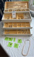 Overall view of open jewelry box with multiple trays of earrings and loose items on table