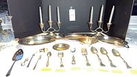Overview of all 19 pieces showing two three-arm candelabras, three oval trays, fluted bowl and assorted flatware and accessories.