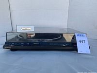 Front view of Technics turntable with dust cover and lot number card.