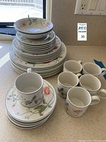 Stacked plates, bowls and mugs on kitchen counter, showing floral pattern of the set.