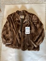 Front view of short brown mink fur coat laid flat showing shawl collar and button closure