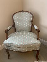 Front view of the light green floral armchair showing wood carved frame and upholstery.
