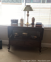 Photo showing the wood console table with dropped leaves, showing the table's design, casters on legs, and some decorative items on the table surface for scale.