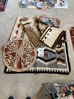 Group of all items arranged on carpet: round tapa cloth, folded rugs, macrame piece