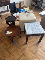 Four accent tables and one storage ottoman displayed together on parquet flooring showing their size and condition.