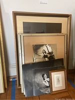Photo showing large and medium framed artworks leaning against wall with smaller framed piece and unframed prints in front, displaying ballet dancers in various poses.
