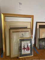 Grouped framed ballet artwork leaning against the wall showing varying sizes and frame styles including gold and bamboo styles.