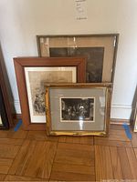 Three framed artwork prints leaning against a wall showing varying sizes and frames.