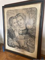 Framed artwork showing two children blowing soap bubbles, detailed in black and white, in a wooden frame.